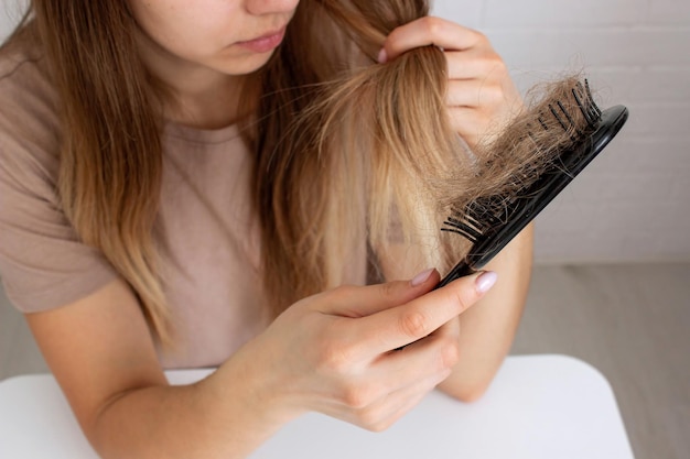 La mujer sostiene un cepillo de cabello y vitaminas de la pérdida de cabello enfoque selectivo