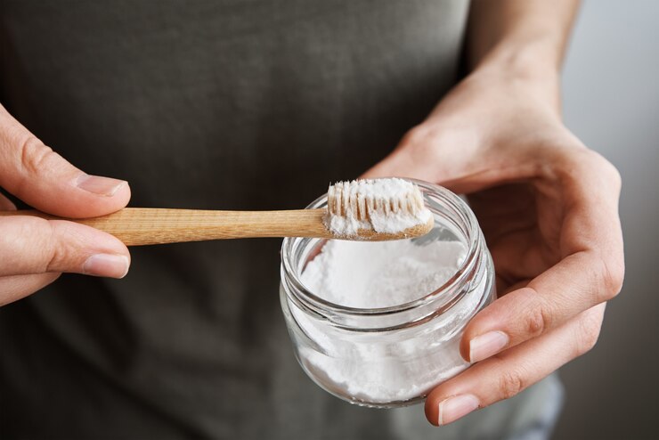 Mujer sostiene cepillo de dientes de bambú y polvo de dientes
