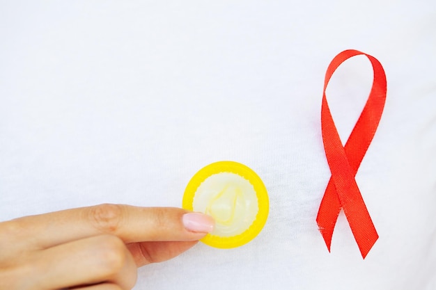 La mujer sostiene un condón y una cinta roja que advierte contra el SIDA