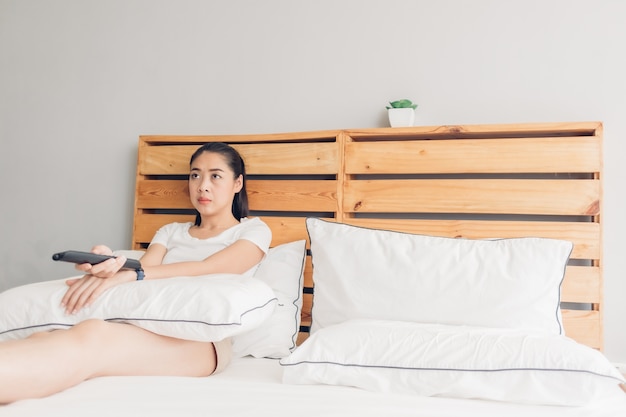 La mujer sostiene un control remoto y está viendo series de televisión dramáticas en serio.