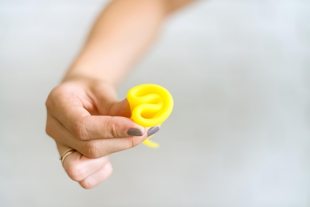 la mujer sostiene una copa menstrual amarilla y muestra cómo usarla