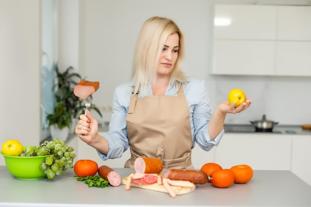 mujer sostiene y elige entre carne y manzana