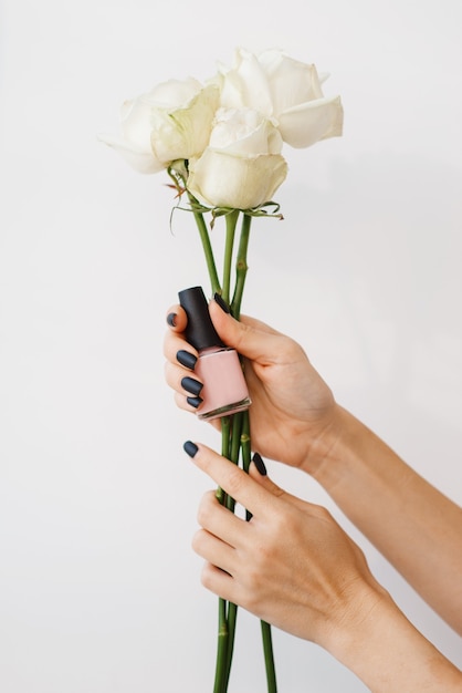 Mujer sostiene flores y esmalte de uñas, salón de belleza