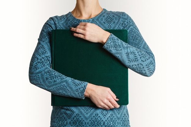 Foto la mujer sostiene el fotolibro familiar cuadrado con impresión con espacio para texto. muestra de álbum de fotos familiar verde en manos de mujer con funda de ante.