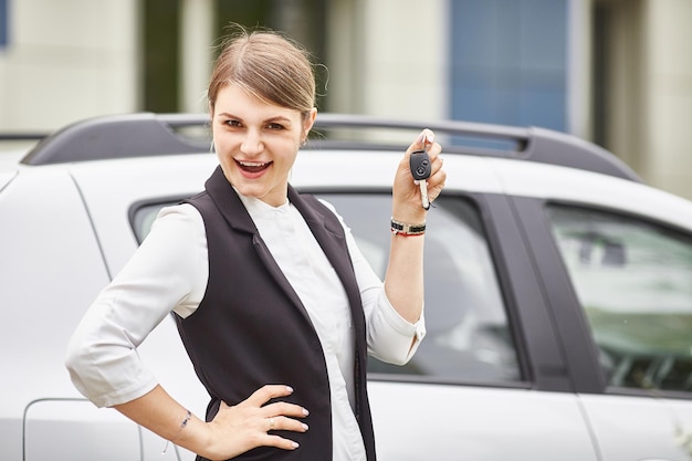 Una mujer sostiene las llaves de un auto nuevo y sonríe a la cámara Entrega de un trabajador de oficina Espacio de taxi femenino para texto