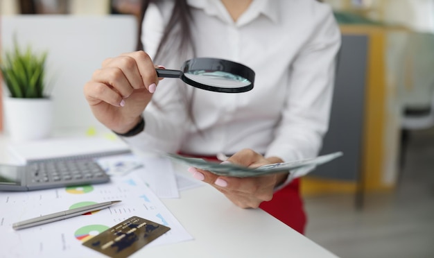 Foto mujer sostiene lupa analizando datos financieros empresariales el administrador calcula las finanzas de la empresa