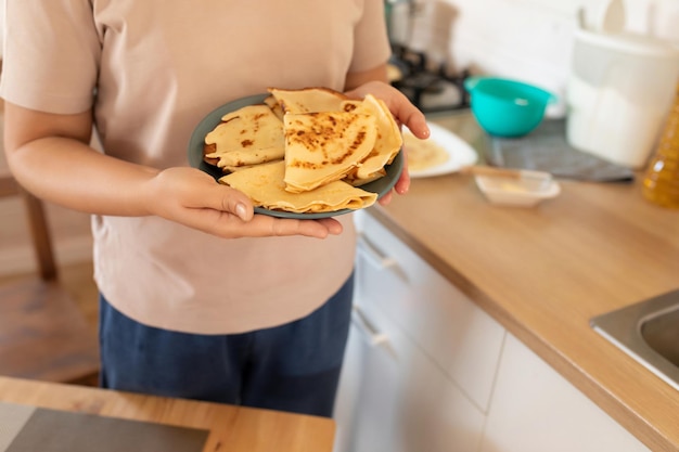 Una mujer sostiene un plato de panqueques preparados para malenitsa