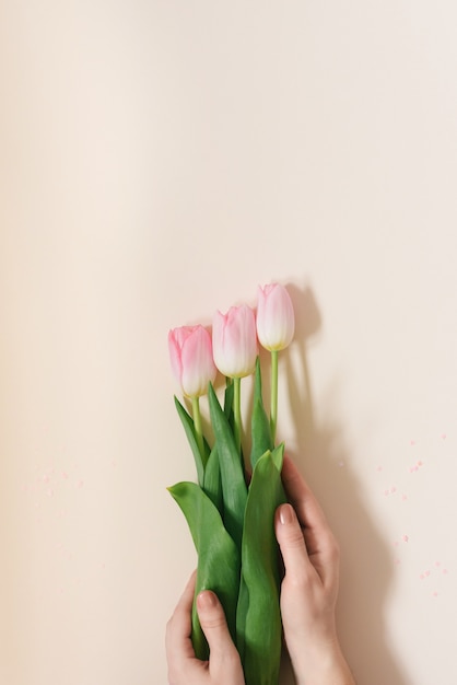 La mujer sostiene un ramo de delicados tulipanes rosados.