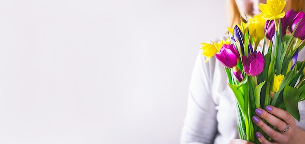 La mujer sostiene un ramo de flores de primavera coloridas