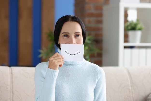 Mujer sostiene una sonrisa pintada en un pedazo de papel emociones positivas y concepto de estado de ánimo