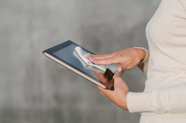 La mujer sostiene su dedo delante de la pantalla de la tableta en blanco