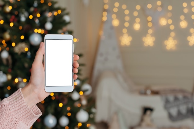 La mujer sostiene su dedo delante del teléfono inteligente en blanco