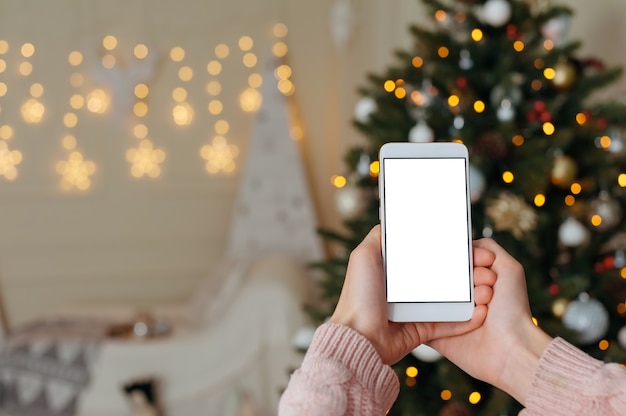 La mujer sostiene su dedo delante del teléfono inteligente en blanco