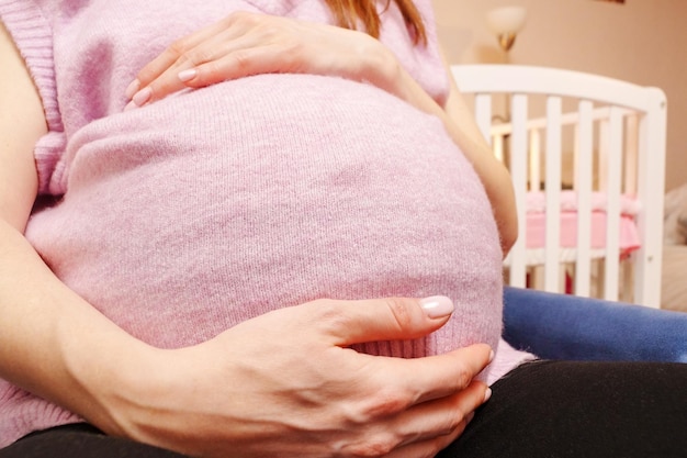 Una mujer sostiene su estómago mientras está sentada en una silla una mujer embarazada está esperando un bebé