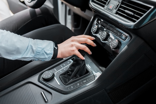 Mujer sostiene su mano sobre la transmisión automática del selector de marchas