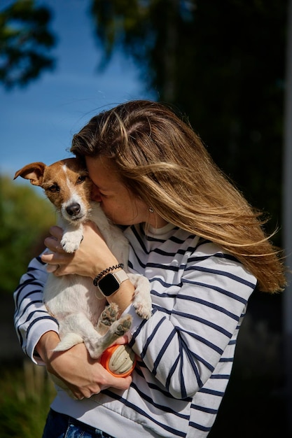 Foto la mujer sostiene a su perro en las manos y abrazando con él feliz dueña mujer abrazando y besando amigo lindo cuidado de mascotas