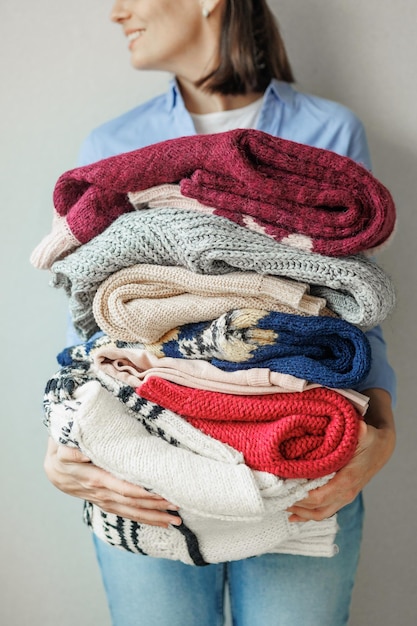 Foto mujer sostiene suéteres de colores y ropa en sus manos lavando y cuidando ropa en polvo y