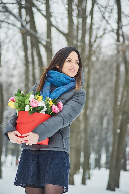 La mujer sostiene en sus manos una caja de regalo roja con un hermoso ramo de flores como regalo para el Día de San Valentín