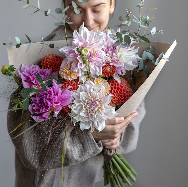 Una mujer sostiene en sus manos un gran ramo festivo con crisantemos y otras flores.