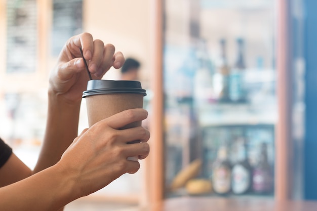 Una mujer sostiene una taza de café en la cafetería al mediodía.