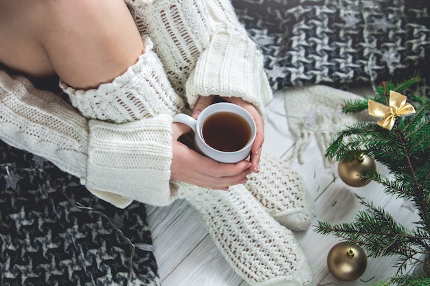 La mujer sostiene una taza de té al lado de sus piernas