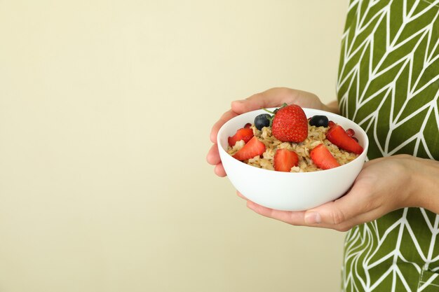 Mujer sostiene tazón de avena sobre fondo beige