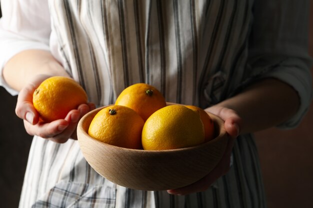 Mujer sostiene un tazón con limones. Fruta madura