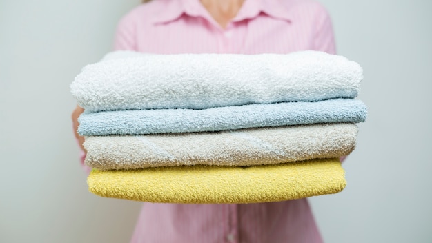 Una mujer sostiene toallas limpias dobladas.