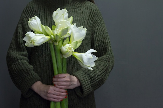 La mujer sostiene varios enormes hippeastrum blancos en sus manos