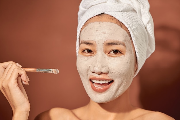 Mujer de spa aplicando mascarilla facial de arcilla. Tratamientos de belleza.