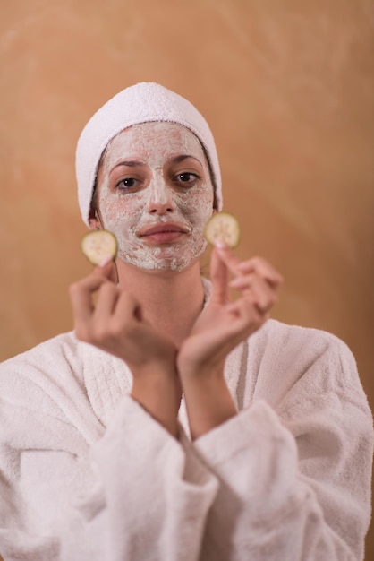 Mujer de spa aplicando tratamientos de belleza con mascarilla facial Retrato de una chica hermosa con una toalla en la cabeza aplicando mascarilla facial