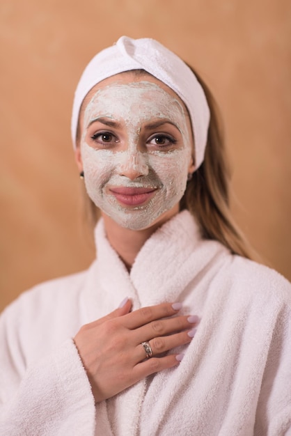 Mujer de spa aplicando tratamientos de belleza con mascarilla facial Retrato de una chica hermosa con una toalla en la cabeza aplicando mascarilla facial