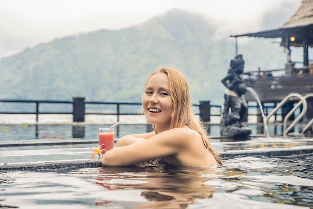 Mujer de spa geotérmico relajándose en una piscina de aguas termales contra el concepto de aguas termales del lago bebiendo guayaba