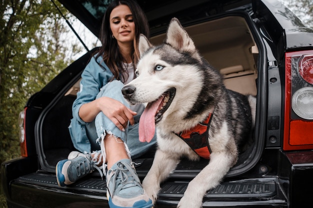 Mujer con su adorable husky viajando en coche