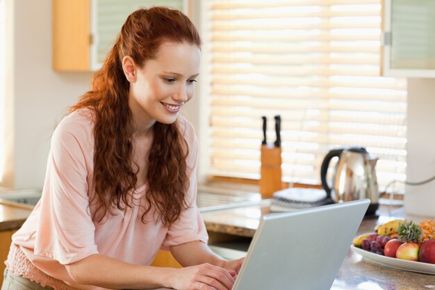 Mujer con su computadora portátil en la cocina