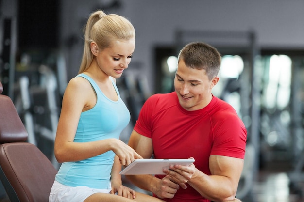 Mujer con su entrenador personal en el gimnasio haciendo ejercicios con pesas