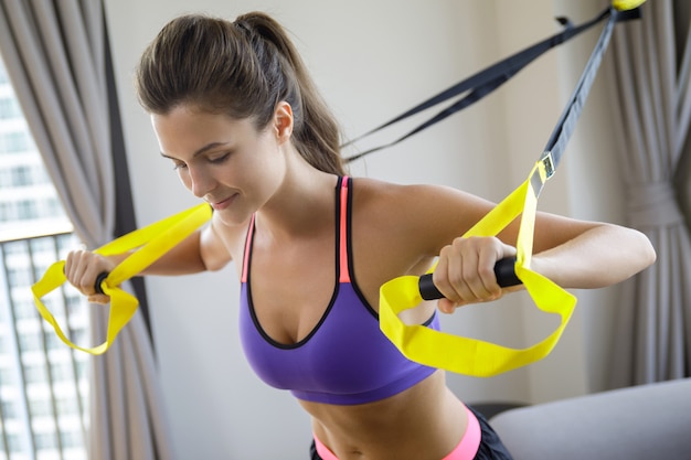 Mujer durante su entrenamiento en casa con correas de suspensión