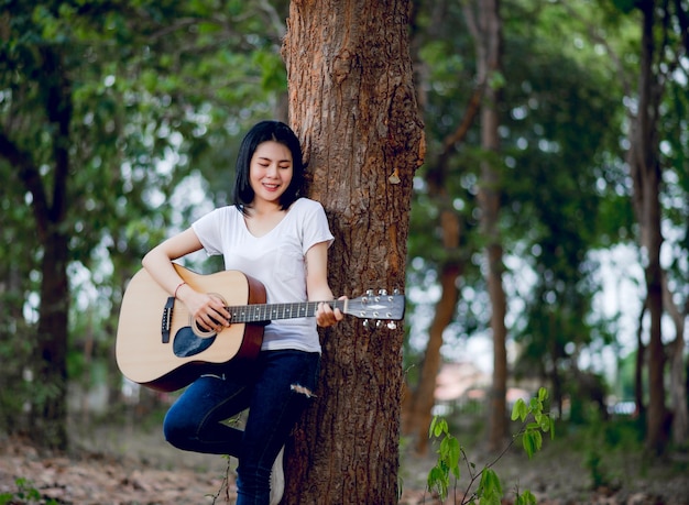 Mujer con su guitarra cantando en la naturaleza