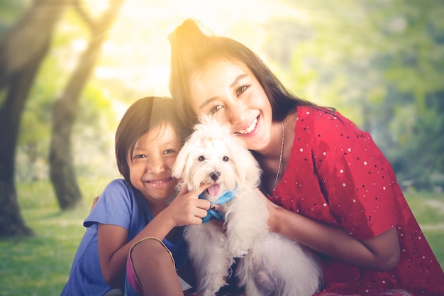 Mujer y su hija abrazando a un perro maltés