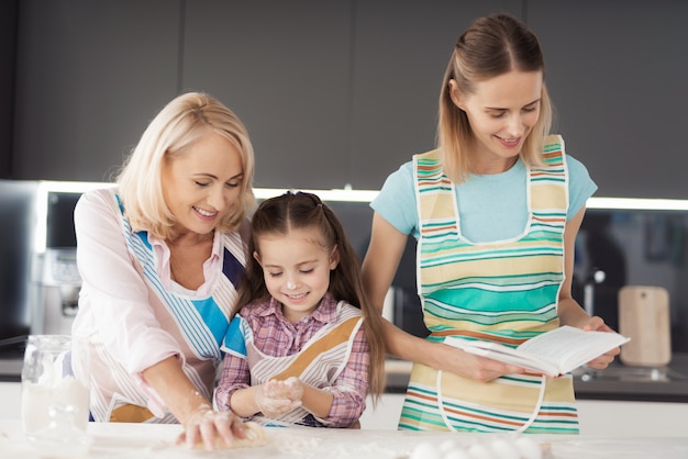 Mujer, su hija y su abuela preparan galletas caseras.