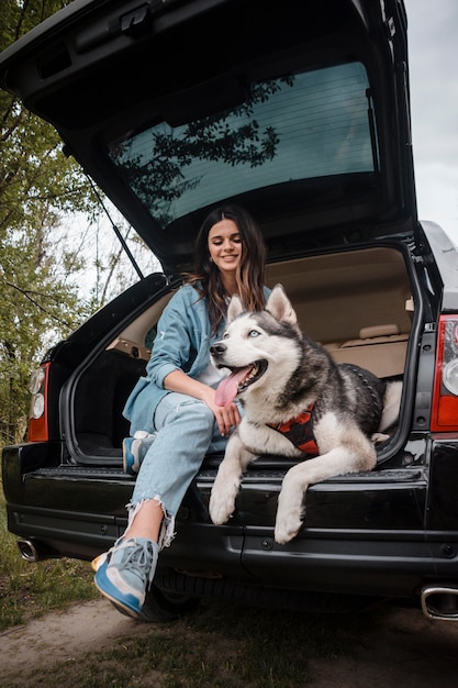 Mujer con su lindo husky viajando en coche