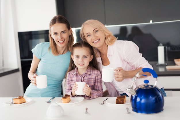 Una mujer, su madre y su hija están bebiendo té.