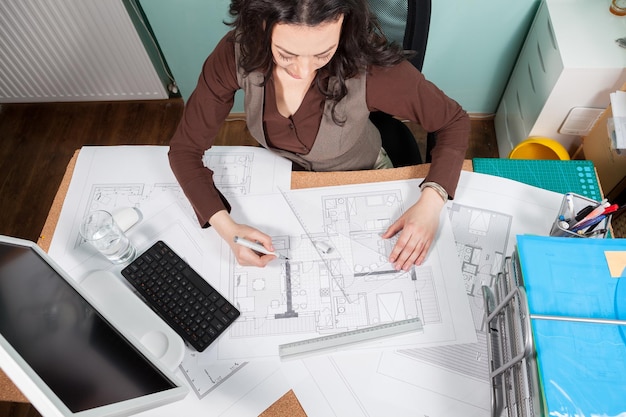 Mujer en su mesa trabajando en planos. Negocios y creatividad. trabajo de arquitectura