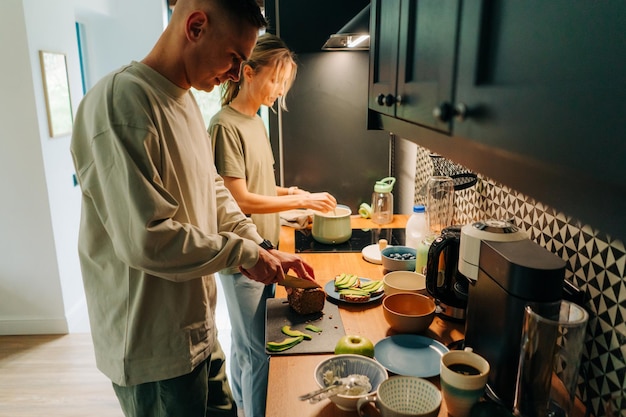 Una mujer y su novio cocinan el desayuno juntos en la cocina de la casa