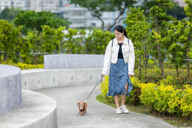 Mujer con su perro dachshund caminando en el parque