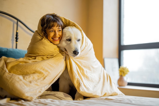 Mujer con su perro debajo de la manta en la cama