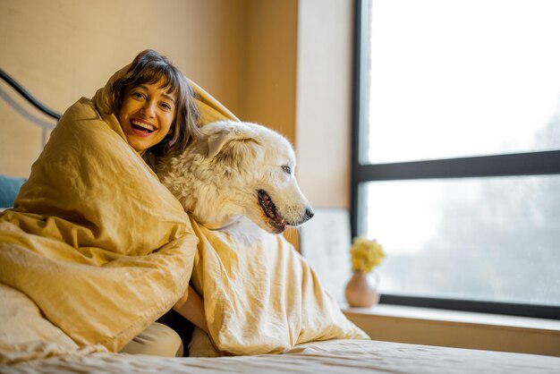 Mujer con su perro debajo de la manta en la cama