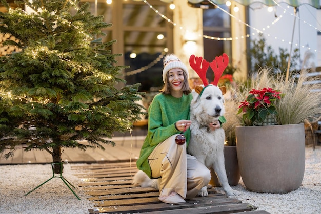 Mujer con su perro en el patio trasero decorado de año nuevo