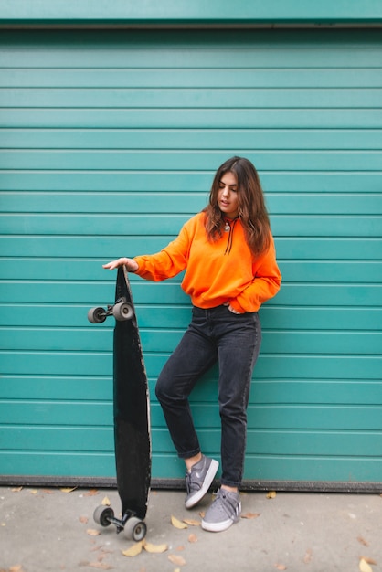 Mujer en sudadera con capucha se encuentra con un longboard