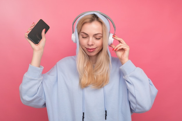 Una mujer con una sudadera con capucha de moda escucha música desde su teléfono